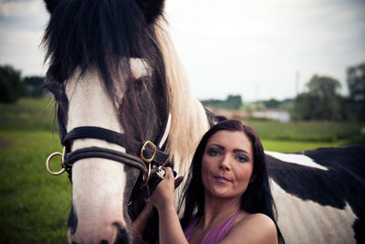 Portrait of young woman with horse against sky