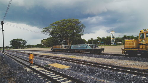 Rear view of monk walking amidst railroad tracks