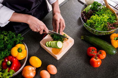 Midsection of man chopping vegetables in kitchen