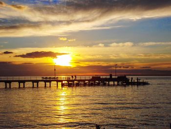 Silhouette pier in sea against sky during sunset