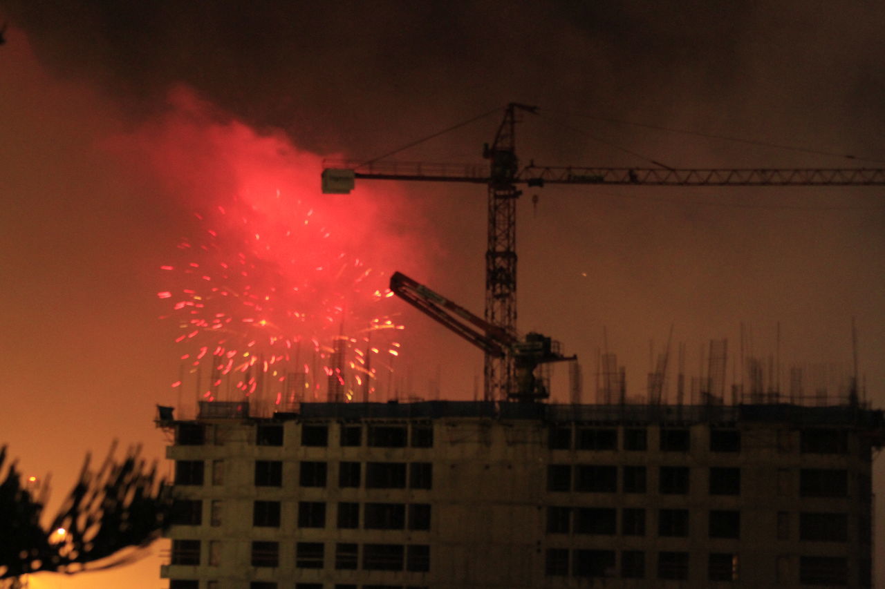 architecture, built structure, building exterior, crane - construction machinery, night, machinery, industry, sky, fireworks, construction industry, city, illuminated, construction site, nature, motion, development, no people, electricity, smoke, outdoors, firework display, light, red, event, evening, building, low angle view, skyscraper, silhouette, celebration