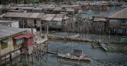 High angle view of fishing boats moored on river amidst buildings in city