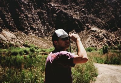 Young man looking away while standing on land