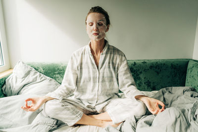 Portrait of young woman sitting on bed at home