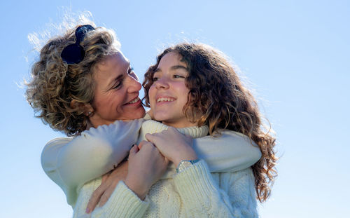 Closeup portrait of smiling mother embracing daughter on sunny day