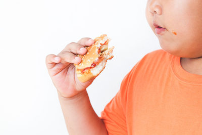 Close-up of boy eating food against white background