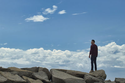 Man standing on rock against sky