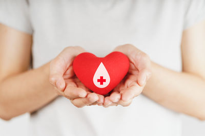 Midsection of woman holding heart shape with hands