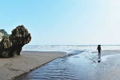 Man walking on beach against clear sky