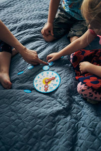 High angle view of people sitting by toy clock on bed