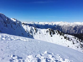 Scenic view of snow covered mountains against blue sky
