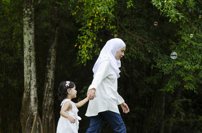 Rear view of couple standing by trees in forest