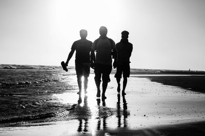 Rear view of people walking on beach