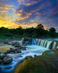 Scenic view of waterfall against sky during sunset