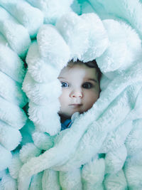 Portrait of cute baby lying on bed wrapped in blanket