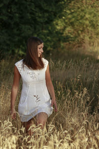 Beautiful woman standing amidst plants on field