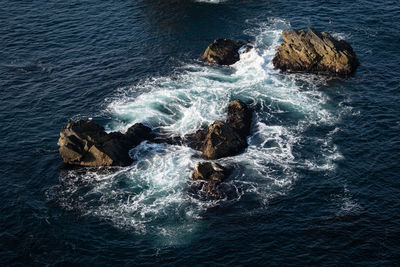 High angle view of waves splashing on rocks