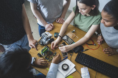 High angle view of multi-ethnic high school students preparing science project at desk in classroom