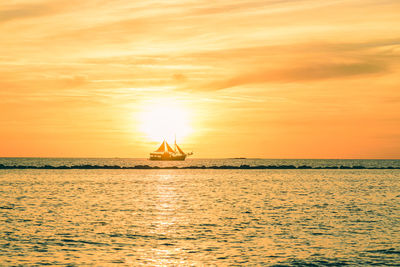 Sailboat sailing on sea against sky during sunset