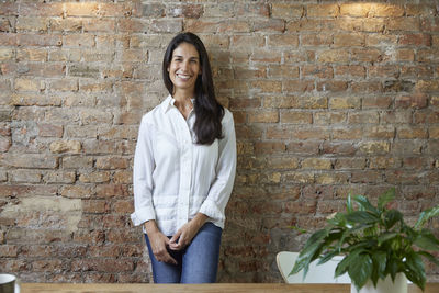 Young woman standing against brick wall