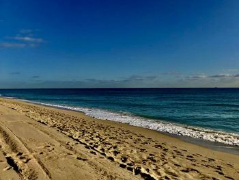 Scenic view of beach against blue sky