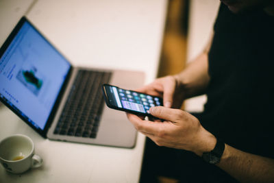 Midsection of man using laptop on table