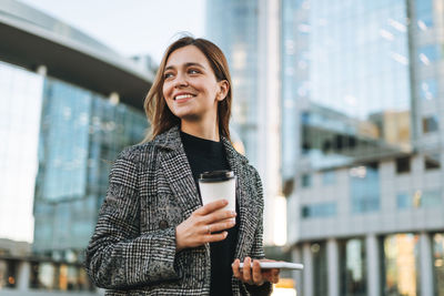 Portrait of young woman standing in city