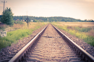 Railroad track amidst field against sky