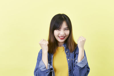 Portrait of smiling young woman against gray background