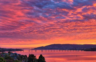 Red sunset reflected in river with bridge