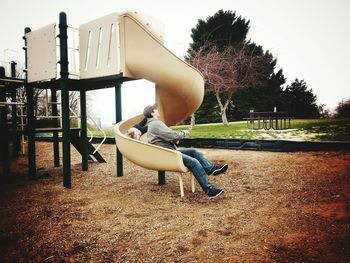 Mother and son enjoying slide at playground