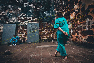 Full length of man and woman walking on tiled wall