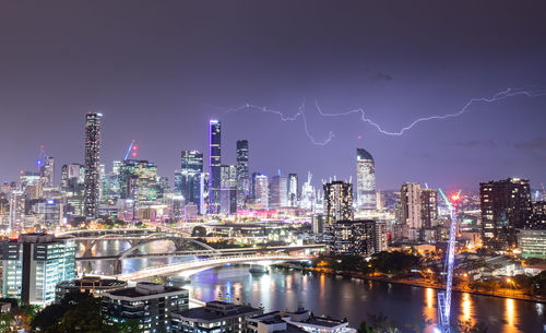 Illuminated buildings in city against sky at night