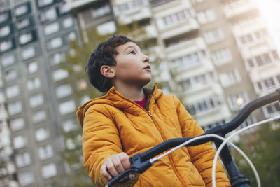 Boy cycling in car against sky