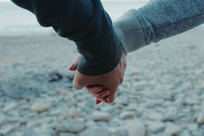 Cropped image of couple holding hands at beach