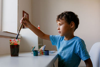 View of boy painting at home