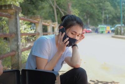 Young woman with mask sitting on street