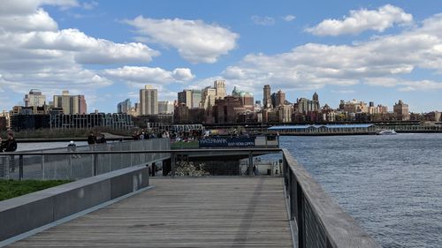 Bridge over river by buildings in city against sky