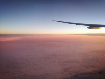 Airplane wing against sky during sunset