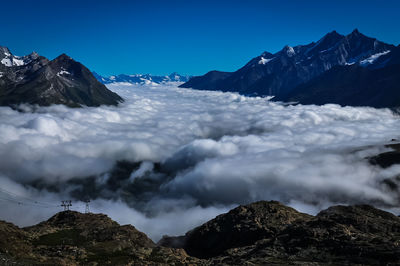 Scenic view of snowcapped mountains against blue sky