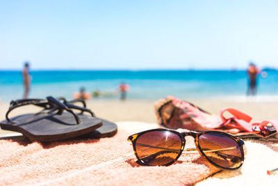 Close-up of sunglasses on sand at beach against clear sky