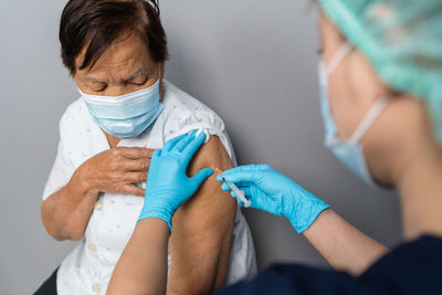 Midsection of doctor vaccinating senior woman in hospital