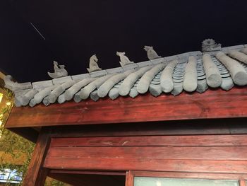 Low angle view of sculpture on roof of building against sky