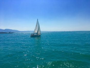 Sailboat sailing in sea against blue sky