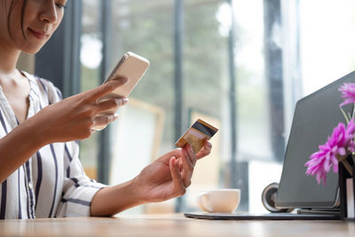 Midsection of man using smart phone on table