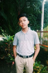 Portrait of young man standing against plants