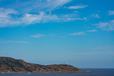 Scenic view of sea by mountain against sky