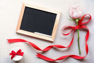Close-up of rose with blackboard on table