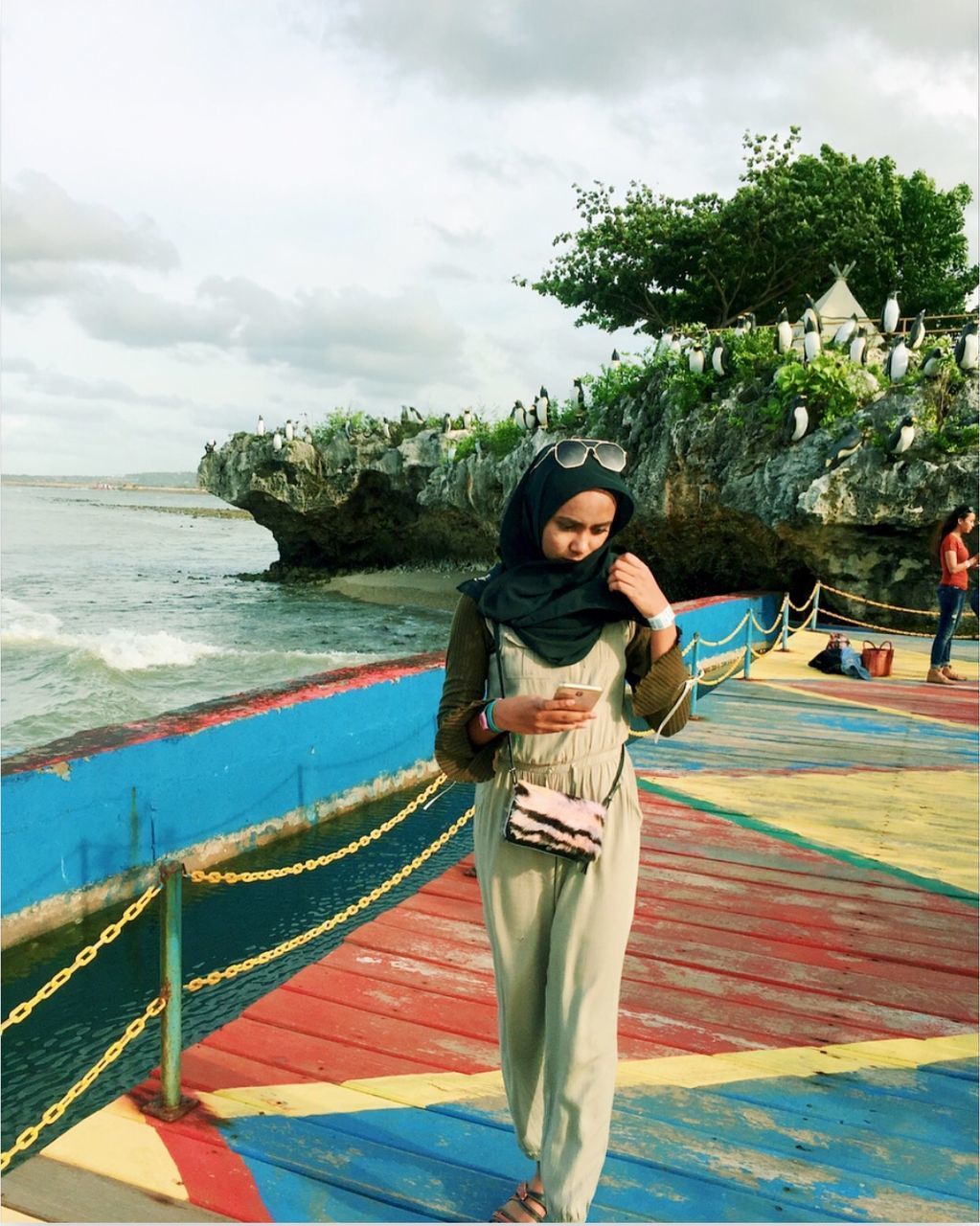 HAPPY YOUNG WOMAN STANDING AGAINST SEA