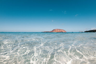 Scenic view of sea against clear blue sky